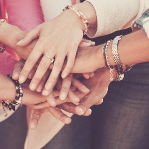 Teamwork and friendship together concept with hands put on hands - women power day for work and friends - caucasian people team in vintage filter colors